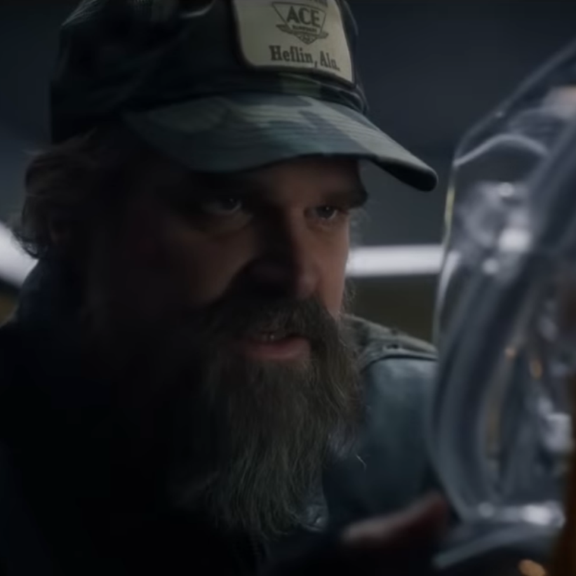 Man with a beard wearing a cap, looking intently at something off-camera.